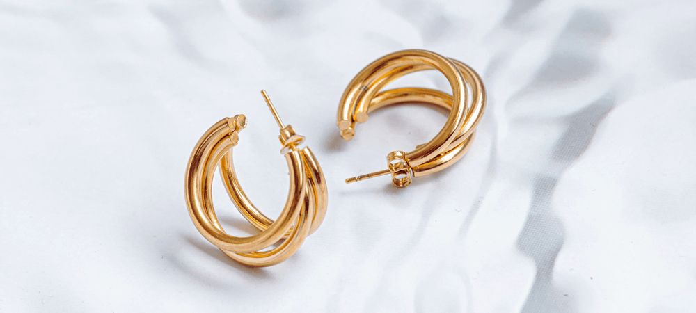 Goldene Creolen auf heller schattiger Oberfläche