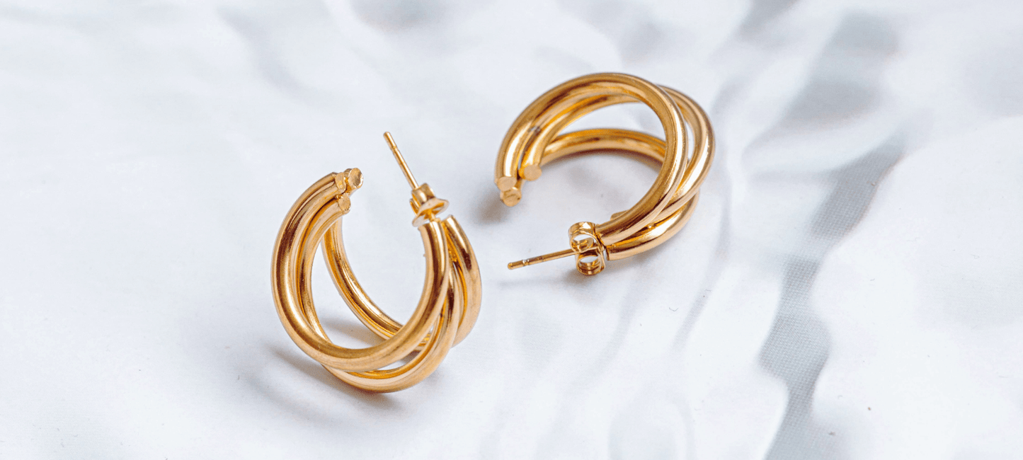 Goldene Creolen auf heller schattiger Oberfläche